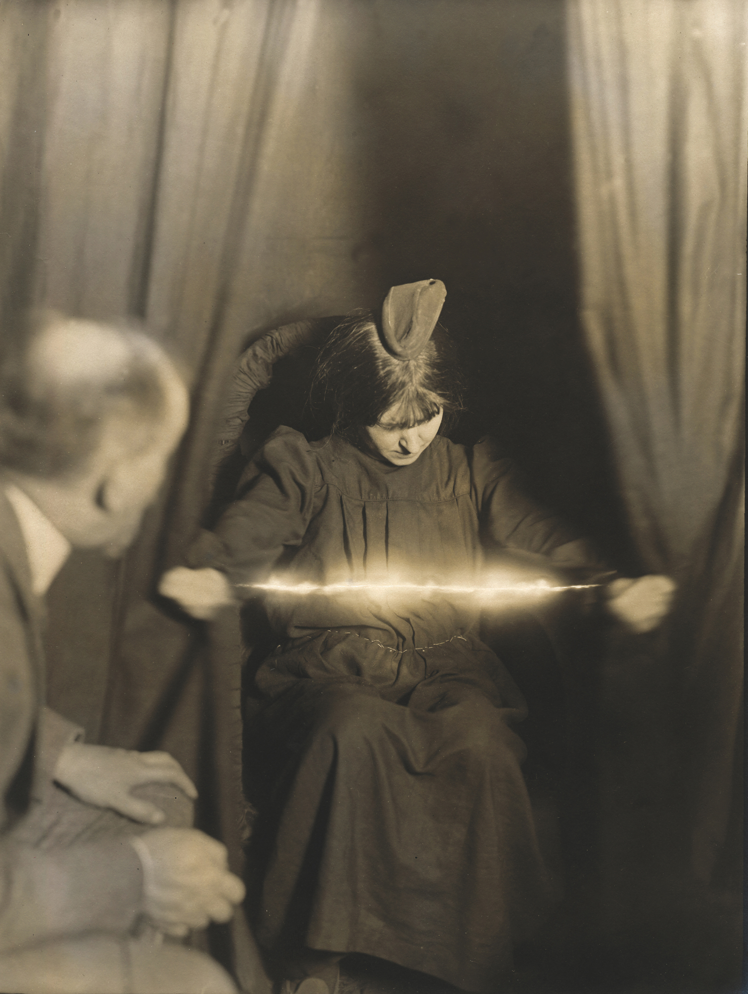 La médium Marthe Béraud avec une matérialisation ectoplasmique sur la tête et une apparition lumineuse entre les mains (1912) Albert von Schrenck-Notzing Collection Institut für Grenzgebiete der Psychologie und Psychohygiene © Adoc-Photos